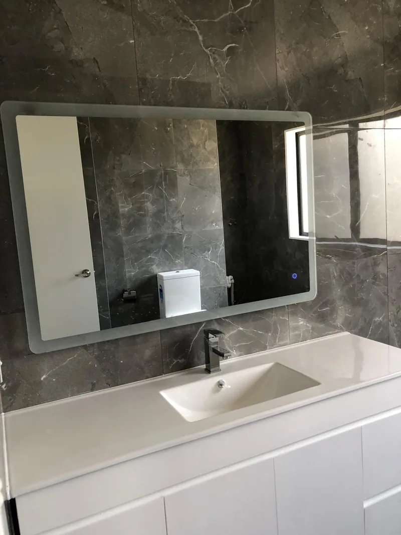White bathroom vanity and mirrored cabinet against dark stone-look tiles